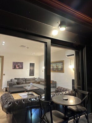 A modern living room with a leather sofa, a coffee table, and a dining area with chairs. - Taksim Bosphorus Hotel (Istanbul)