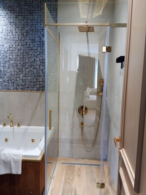 Un baño moderno con ducha envuelta en vidrio, una bañera independiente y pared de azulejos.