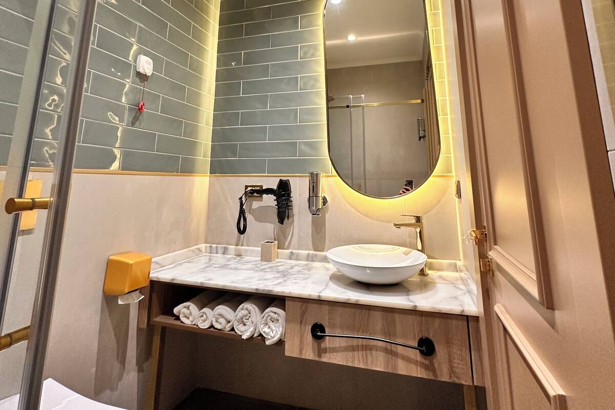 A bathroom with a white sink, a mirror, and a towel rack.