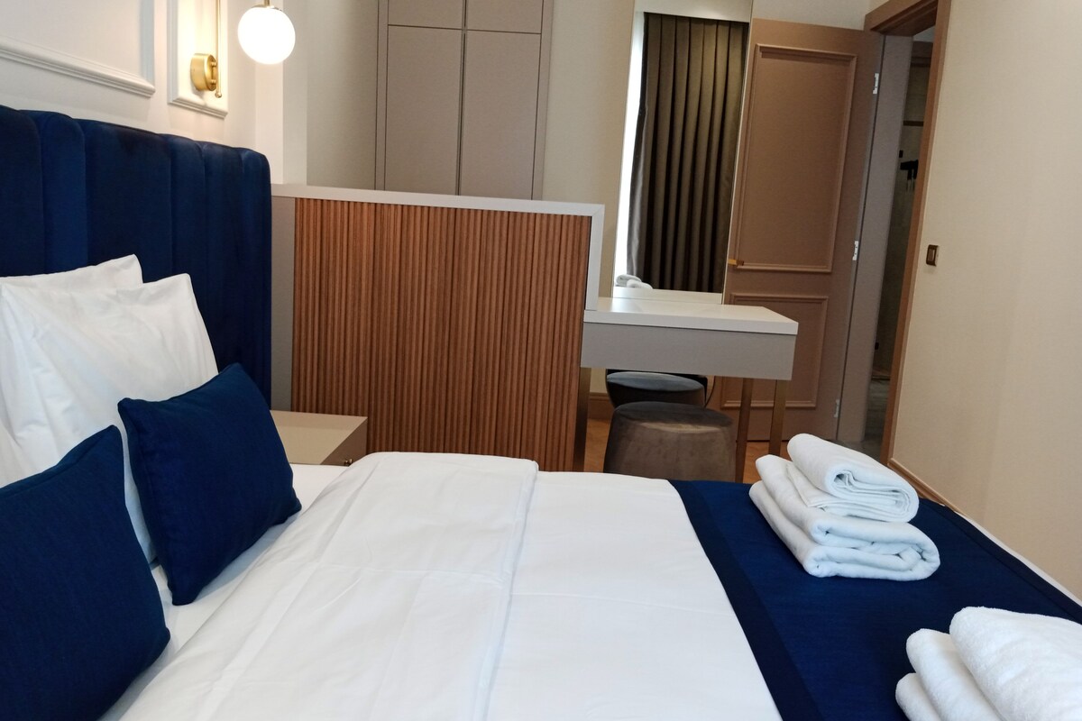 A hotel room with a bed, a desk, a mirror, and a wardrobe.