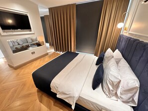 A modern hotel room with a large bed, a TV mounted on the wall, a seating area with cushions, and a large window with curtains. - Taksim Bosphorus Hotel (Istanbul)