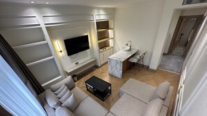 A modern living room with a large sofa, a TV, and a kitchen area with a marble countertop. - Taksim Bosphorus Hotel (Istanbul)