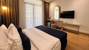 A hotel room with a bed, a desk, a TV, and a window with curtains. - Taksim Bosphorus Hotel (Istanbul)