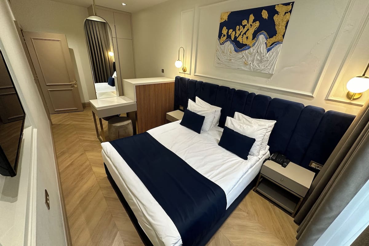 A modern hotel room with a large bed, a desk, and a vanity.