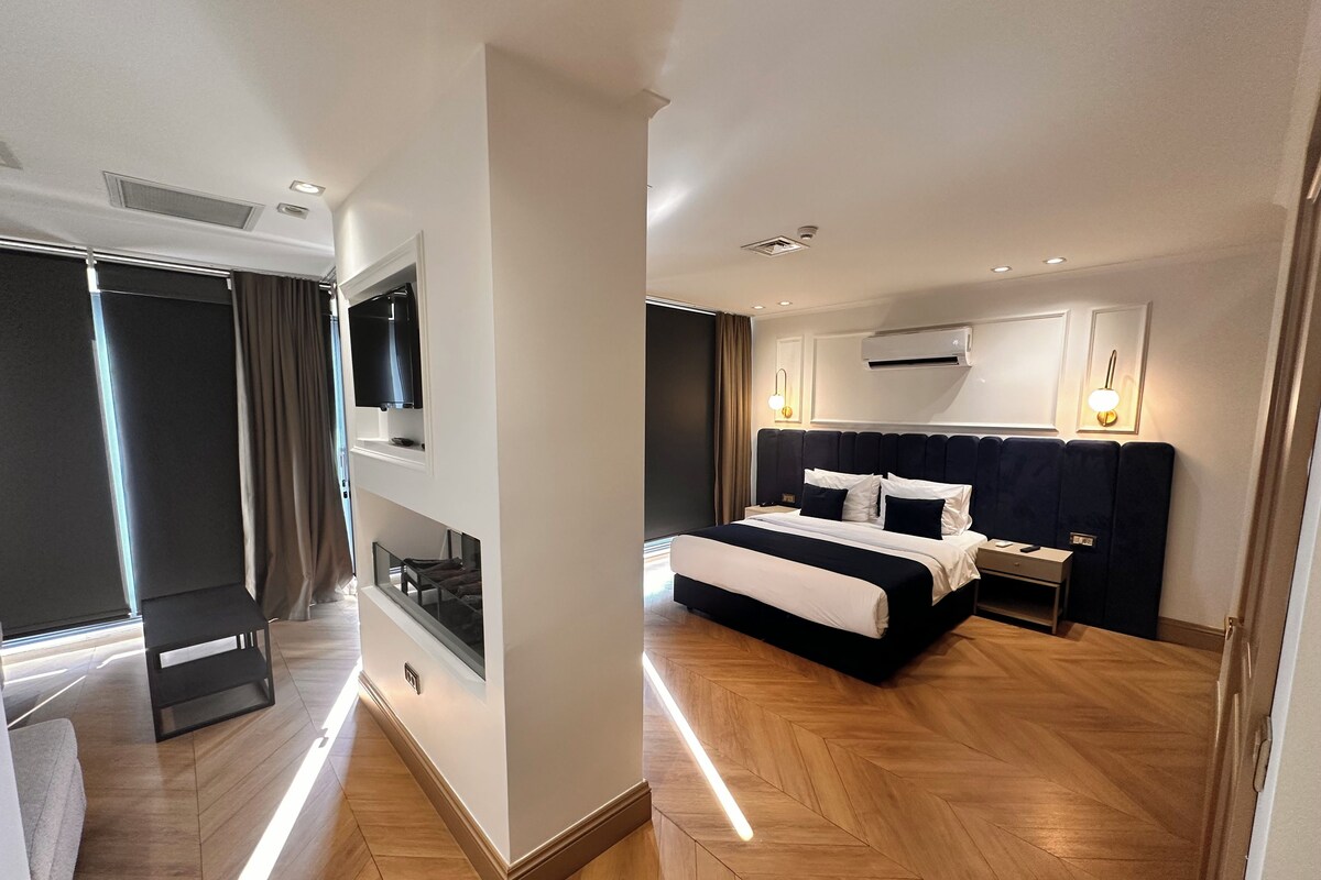 Habitació d'hotel moderna amb un llit gran, televisió integrada, aire condicionat i vista a la ciutat.