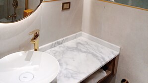 A bathroom with a white marble sink, green tiled walls, and a gold showerhead. - Taksim Bosphorus Hotel (Istanbul)