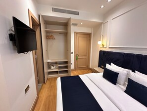 Habitació d'hotel amb llit, taulell de nit, televisió, armari i vestidor.