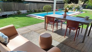 Eine Terrasse mit Pool, Gartenmöbeln und einer Holzterrasse.