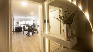 A modern interior with a wooden floor, a dining area with chairs and a table, and a hallway leading to a room with a door marked '205'.