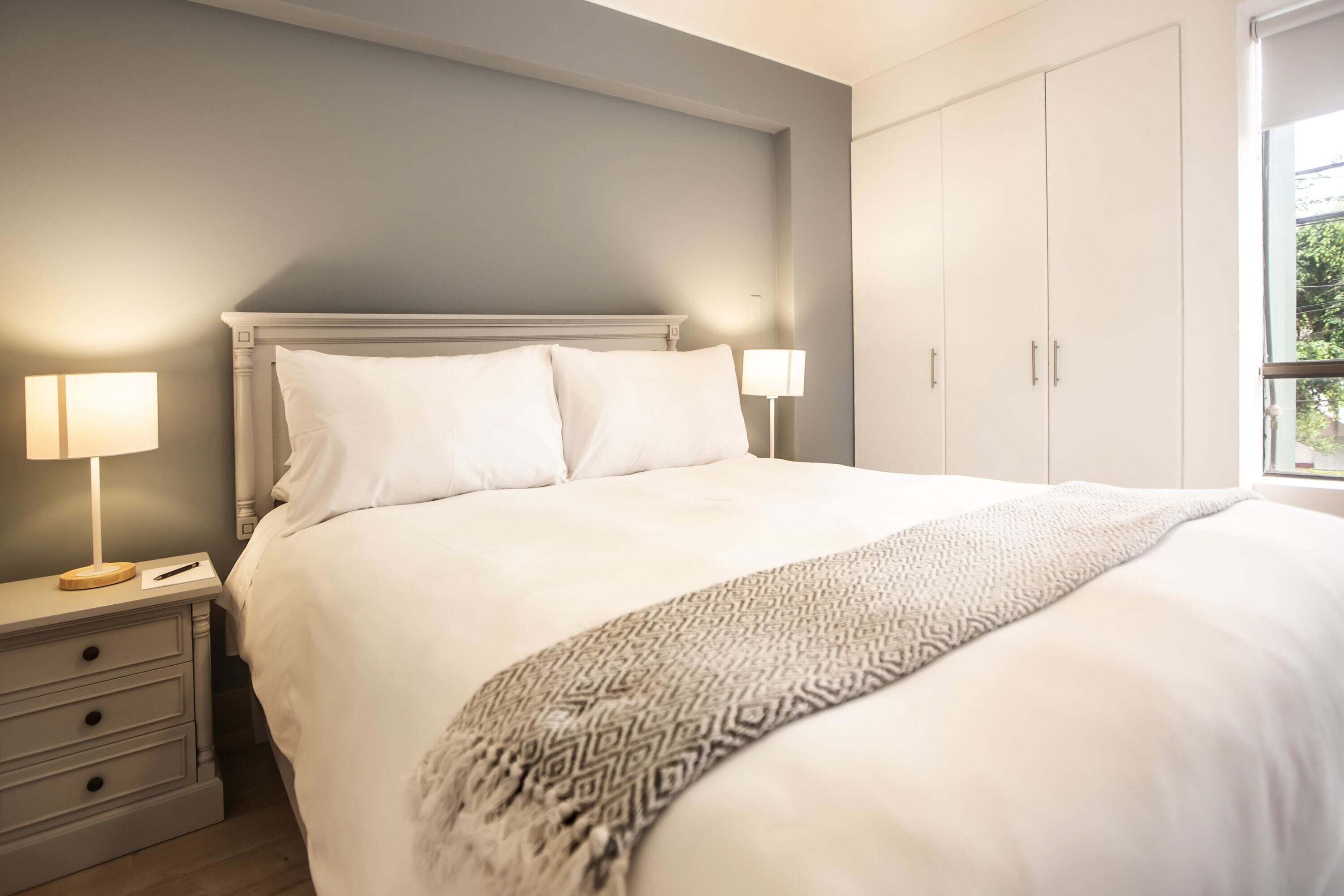 Ein Schlafzimmer mit Bett, Nachttischen, einer Lampe und einem Kleiderschrank.