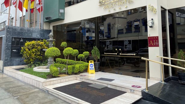 A hotel entrance with a sign reading "San Martin Apart-Hotel" and flags of various countries.