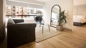 A modern living room with a sofa, a glass coffee table, a large mirror, and a potted plant.