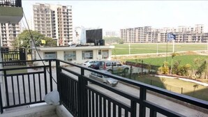 Ein Balkon mit Blick auf eine Wohngegend, darunter eine Straße mit Autos und ein Sportplatz.