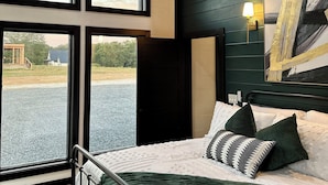 Un dormitorio con una cama grande, varias ventanas y vistas al exterior.
