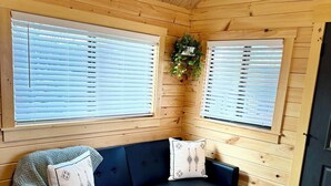 A cozy room with a dark blue sofa, two white pillows, a wooden coffee table, and a patterned rug. - Cozy Cabin with Private Resort Amenities: Walking Distance to Lake James (Marion)