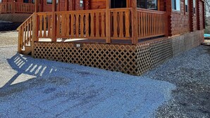A wooden cabin with a porch, a covered deck, and a gravel driveway. - Cozy Cabin with Private Resort Amenities: Walking Distance to Lake James (Marion)