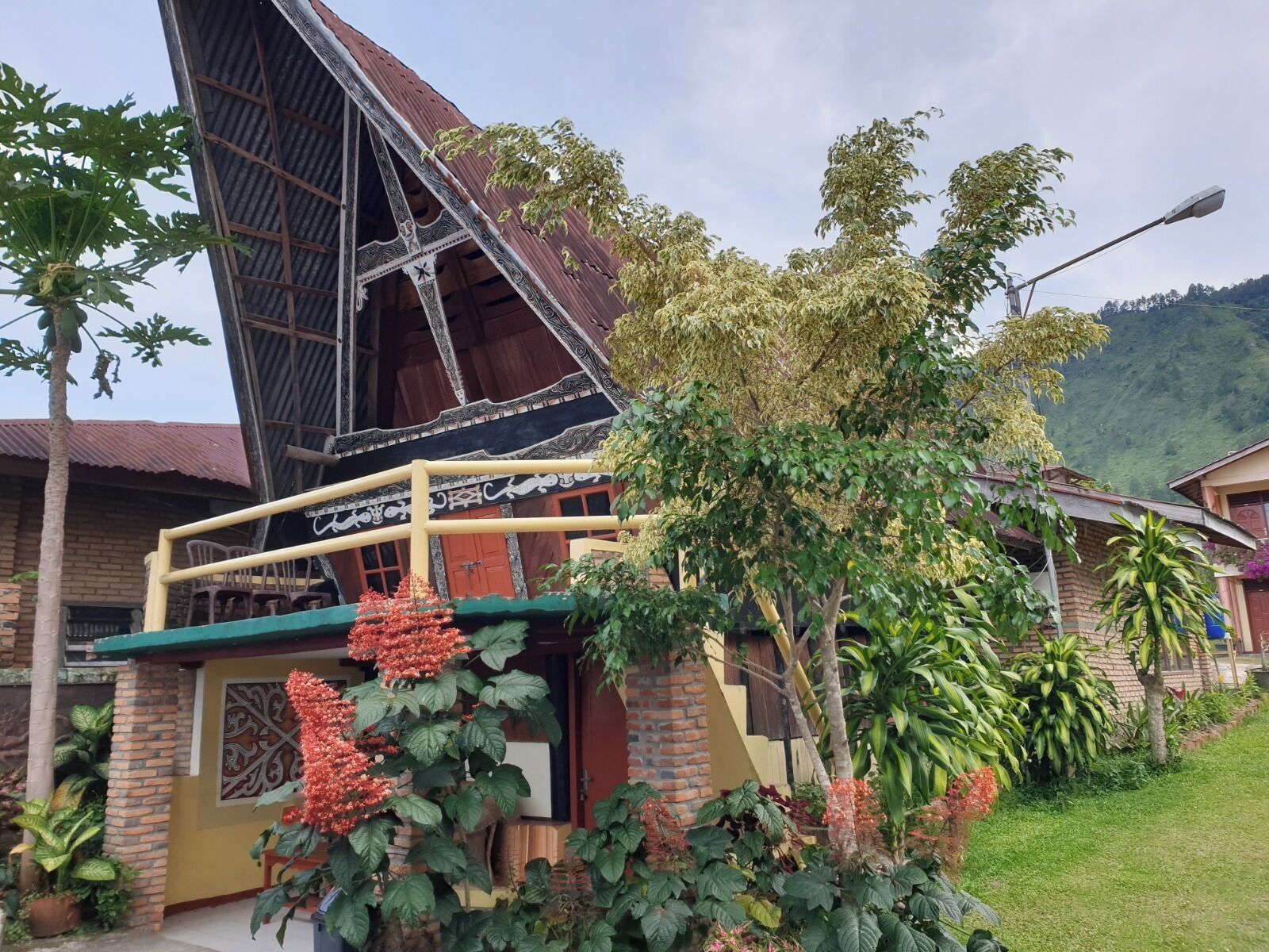 Una casa tradicional con techo inclinado, balcón y jardín con diversas plantas.