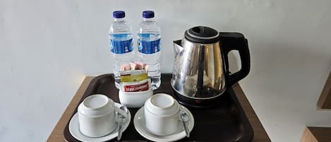 A tray with two white cups, two water bottles, a MaxCreamer container, and a black electric kettle.