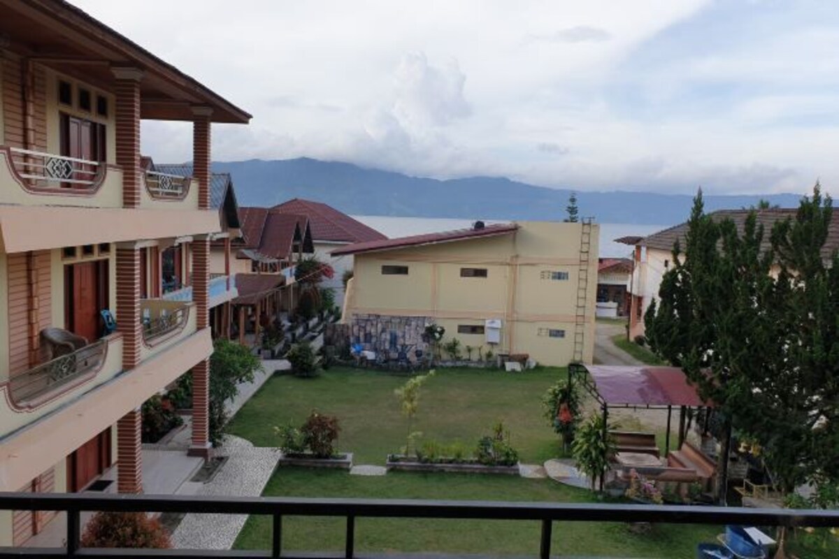 A hotel with multiple floors, balconies, and a central courtyard with a lawn and seating area.