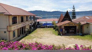 Un hôtel doté d’un espace de réception, d’un coin salon extérieur abrité et offrant une vue sur un lac et des montagnes en arrière-plan.