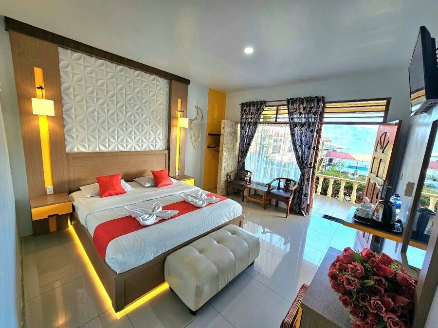 A modern hotel room with a large bed, a balcony with a view, and a well-lit space.