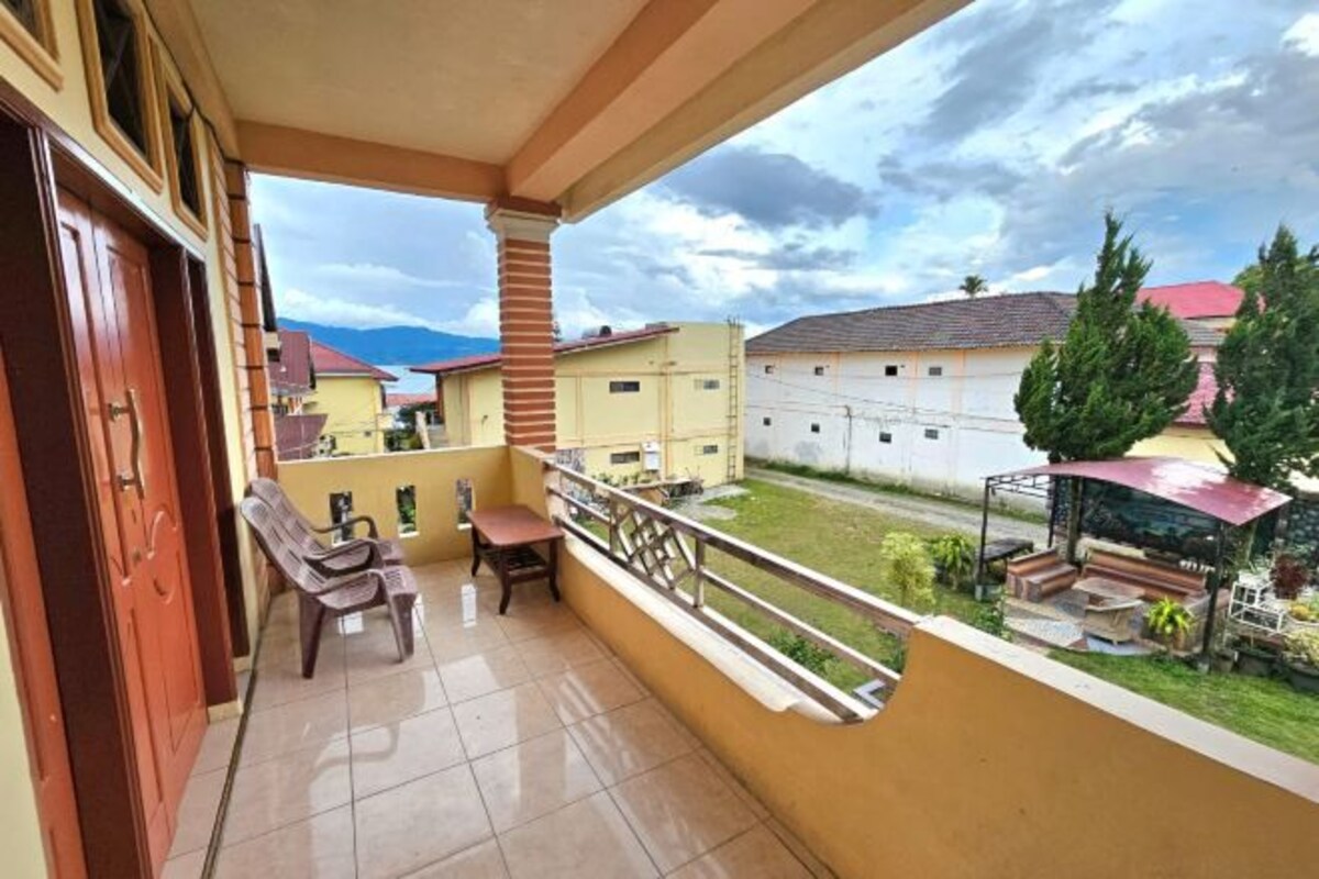 A balcony with a view of neighboring houses, a tiled floor, and a wooden door.