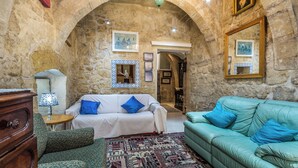 Une pièce chaleureuse avec un mur en pierre, un tapis à motifs et deux canapés ornés de coussins bleus.