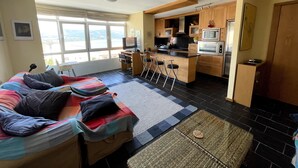 A compact living space with a sofa, a small kitchen area, and a view through large windows. - The apartment is located in front of Langosteira beach, with stunning views. (Fisterra)