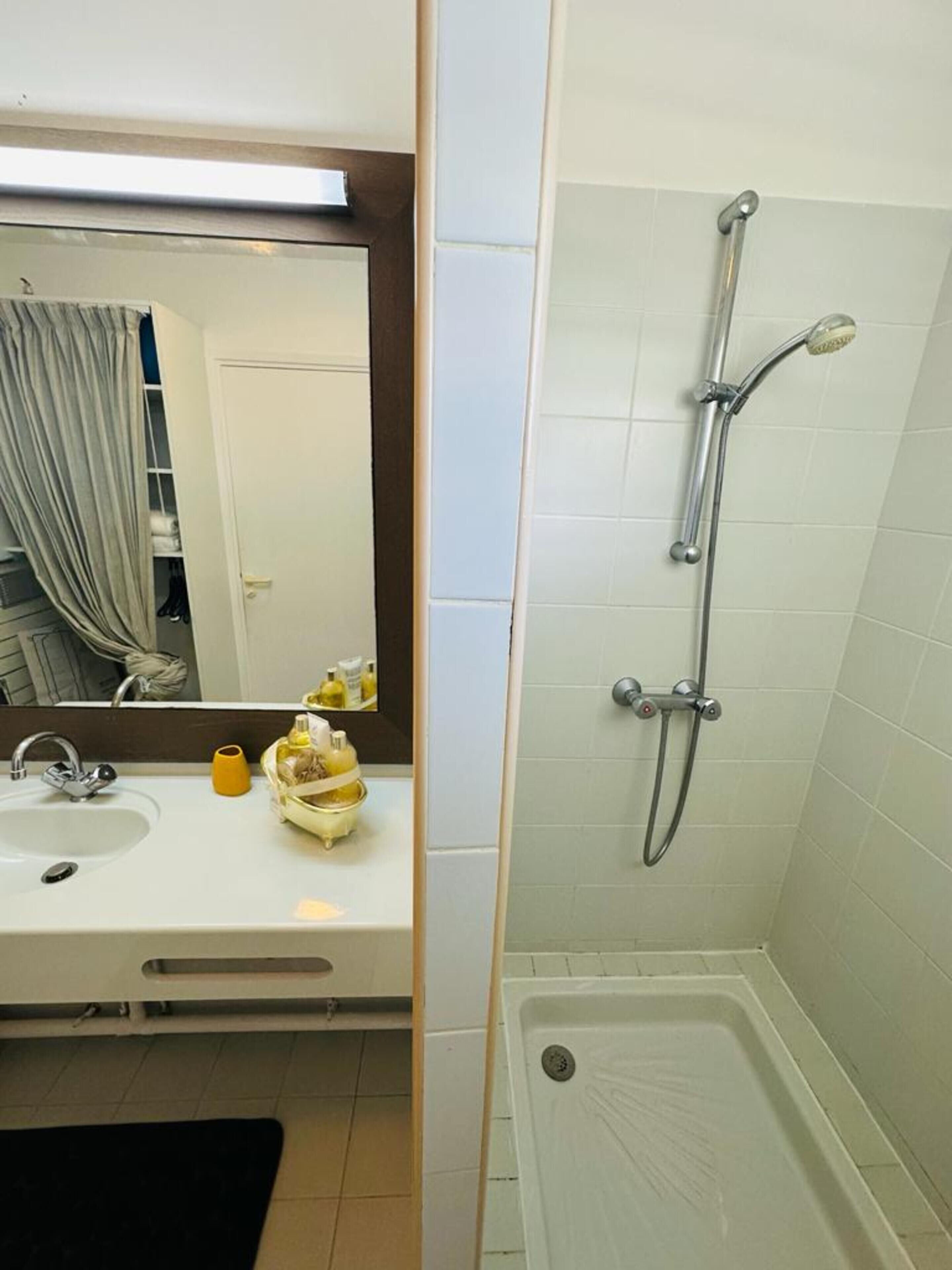 A bathroom with a sink, mirror, and shower.