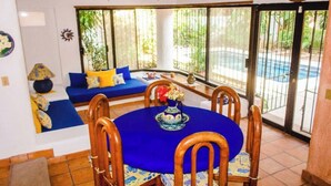 Een eethoek met een ronde tafel, vier houten stoelen en een blauwe tafelkleed.