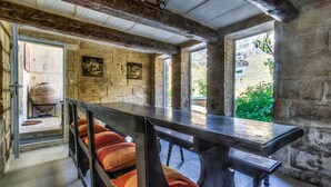 Un intérieur rustique avec des murs en pierre, une table en bois et des bancs dotés de coussins.