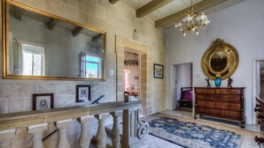Un vaste hall avec un sol en marbre, un grand miroir, un lustre et une commode en bois dotée d’un miroir.
