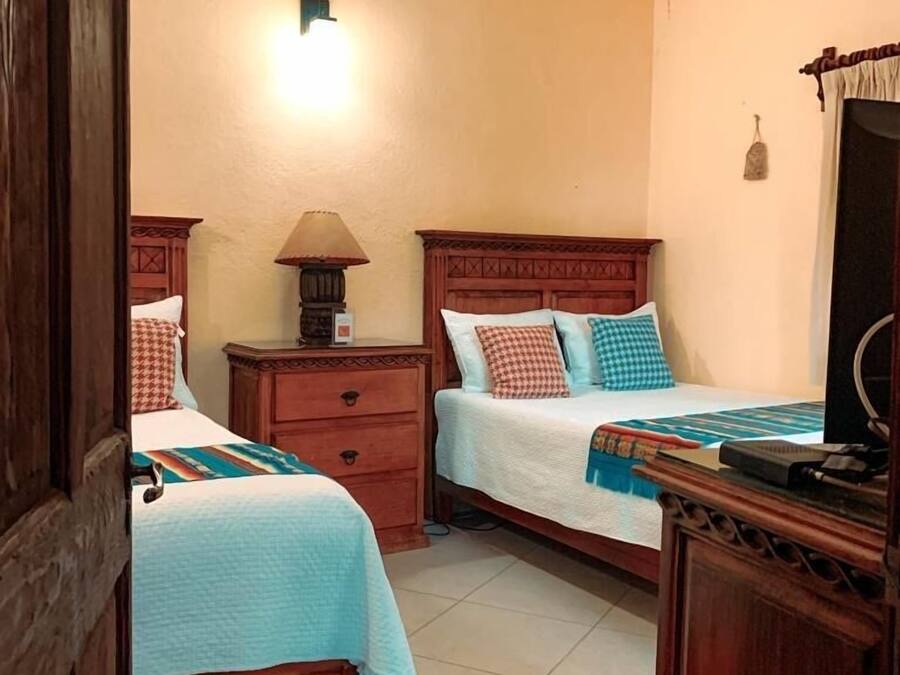 Een hotelkamer met twee bedden, een nachtkastje, een lamp en een houten dressoir.