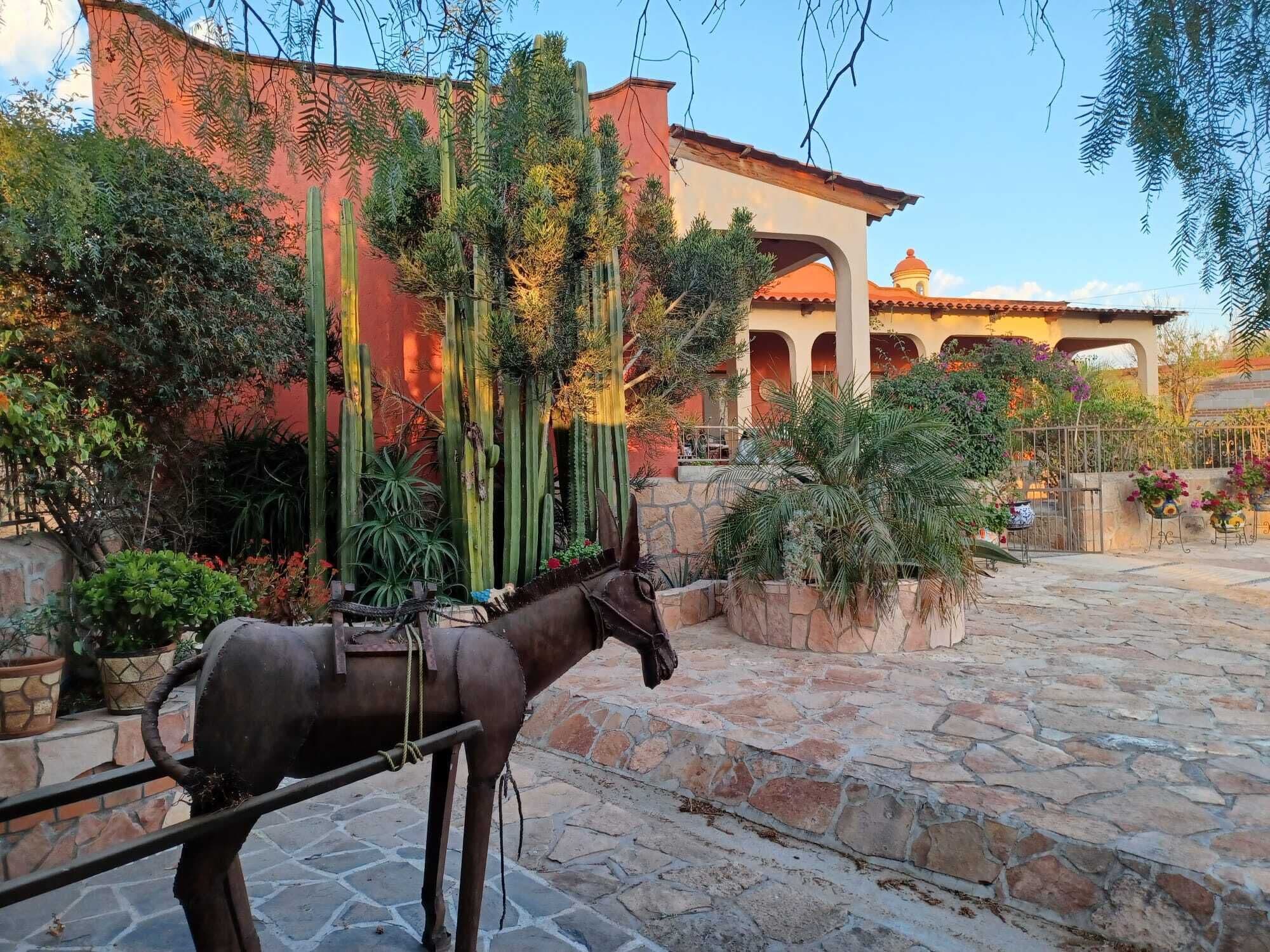 A courtyard with a horse-drawn carriage, stone flooring, and a building with arches and a dome.