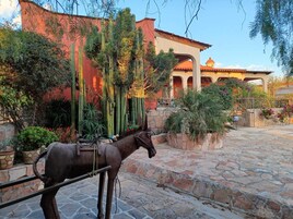 A courtyard with a horse-drawn carriage, stone flooring, and a building with arches and a dome.