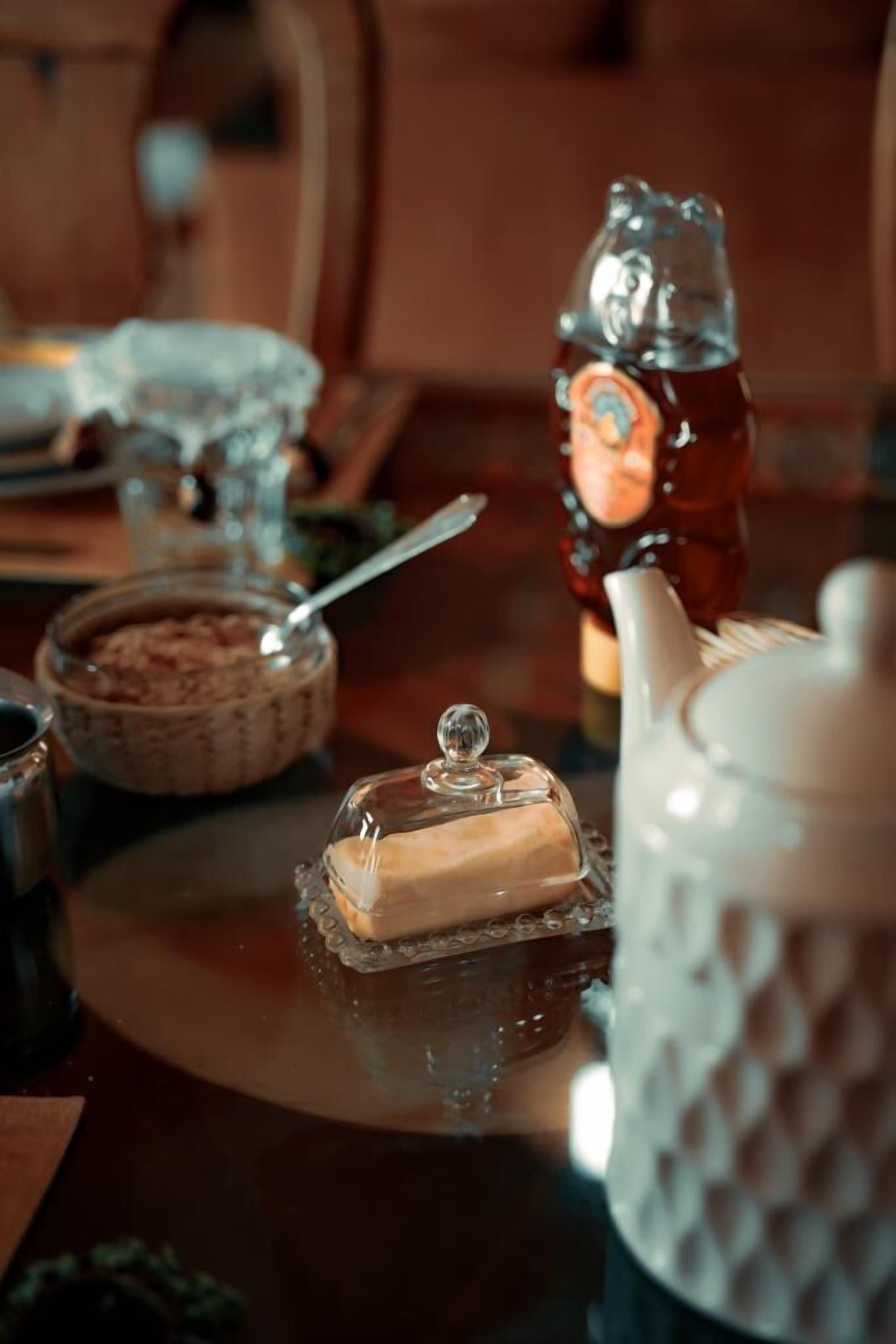 A table with a teapot, a sugar bowl, and a glass container with a lid.