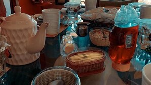 A dining table with various dishes, a teapot, and a sign on the wall. - CASONA DOS VIDAS (Tequisquiapan)