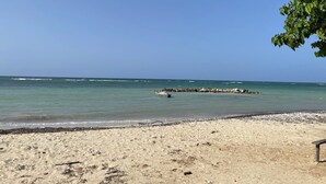 A sandy beach with a rocky outcrop and calm sea.