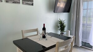 A dining area with a table, chairs, a wine bottle, and a potted plant.