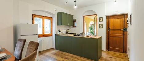 A compact kitchen with a central island, wooden flooring, and a dining area with chairs.