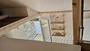 A room with a high ceiling and a sloped roof, featuring a netted play area with multiple birdcages.