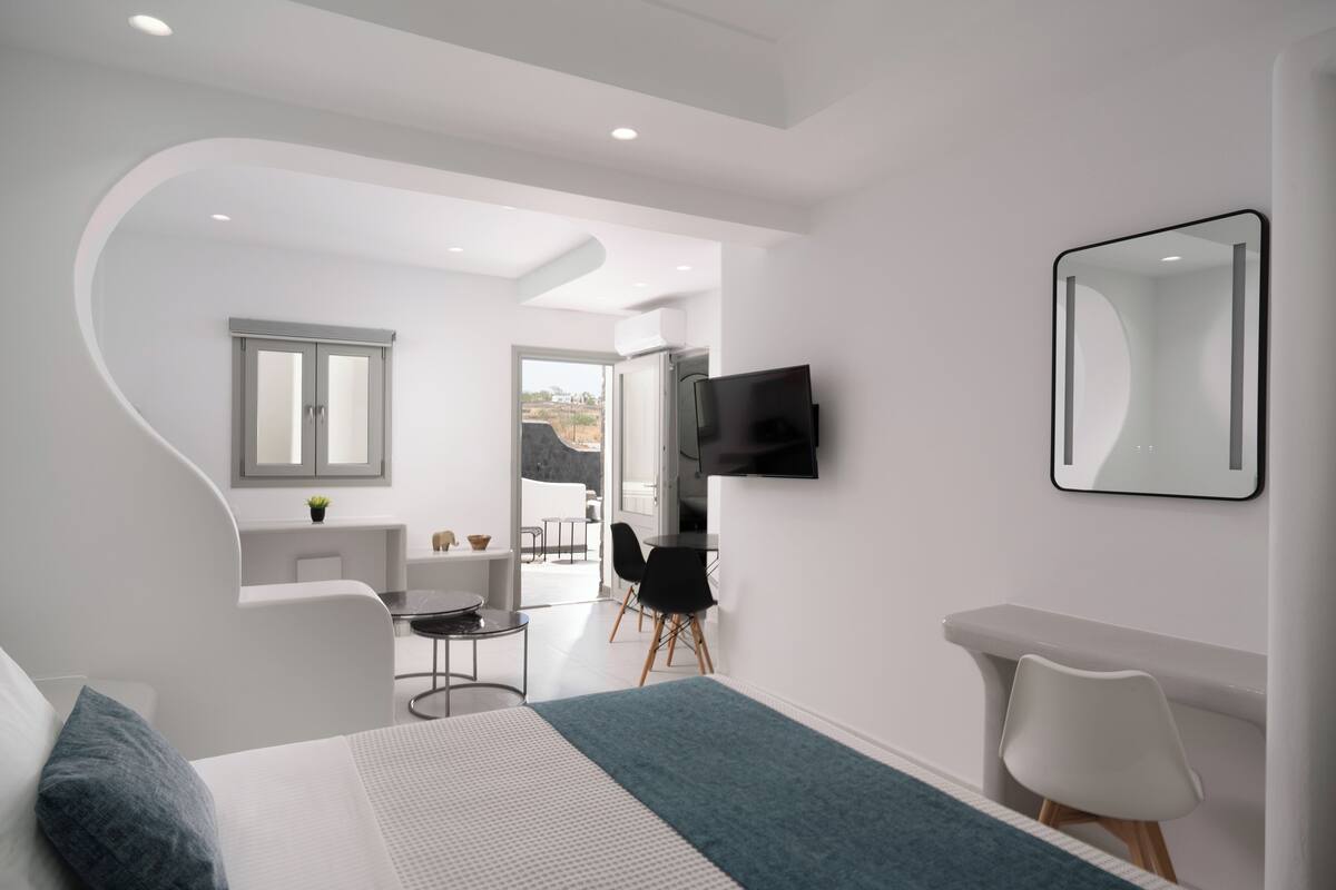 Una habitación de hotel moderna con una cama, un escritorio, una silla, un televisor y un baño.