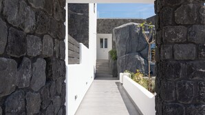A modern architectural hallway with stone walls, a straight pathway, and recessed lighting. - Griseo Villas (Santorini)