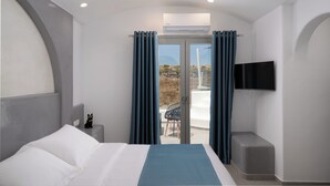A bedroom with a bed, a TV mounted on the wall, and a view of the outdoors. - Griseo Villas (Santorini)