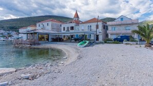 Un edifici a la costa amb una torre destacada, una platja al davant i un vaixell petit.