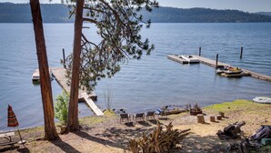 A lakeside dock with boats, a picnic table, and chairs. - Lakefront Bliss: Coeur d'Alene Cabin w/ Dock! (Coeur d'Alene)