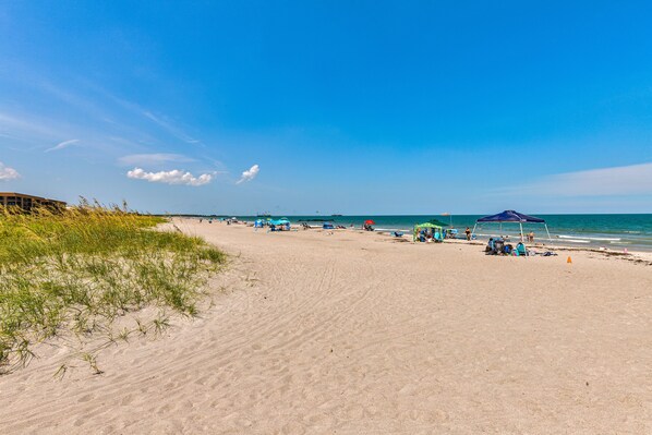 Relax on the pristine beach with comfortable seating and umbrellas.