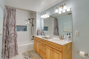 Ein Badezimmer mit Badewanne, Waschtisch mit Spiegel und Dusche.