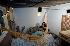 A hammock chair in a room with a rustic design, featuring a brick wall, wooden logs, and a tiled backsplash. - Viveka Experience (Medellín)