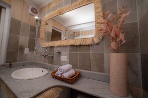 Um banheiro com pia, espelho e um vaso decorativo.